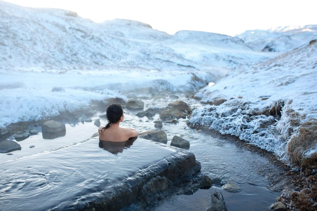 Iceland Hot Springs, hot springs in Iceland, The girl bathes in a hot spring in the open air with a gorgeous view of the snowy mountains. Incredible iceland in winter, Hrunalaug hot spring in the golden circle in Iceland