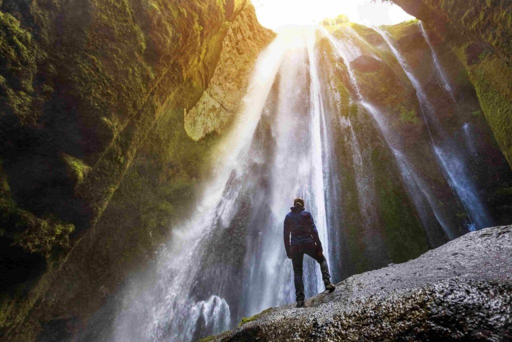 woman standing inside the canyon watching Gljufrabui waterfall in south Iceland