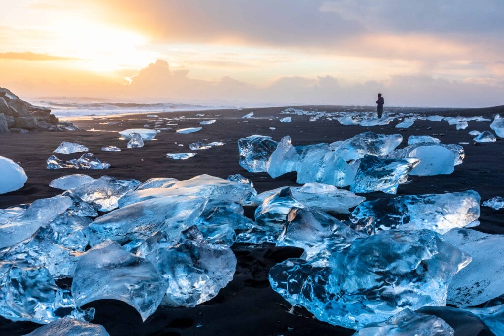 man standing and watching the sunset at Diamond Beach in south Iceland