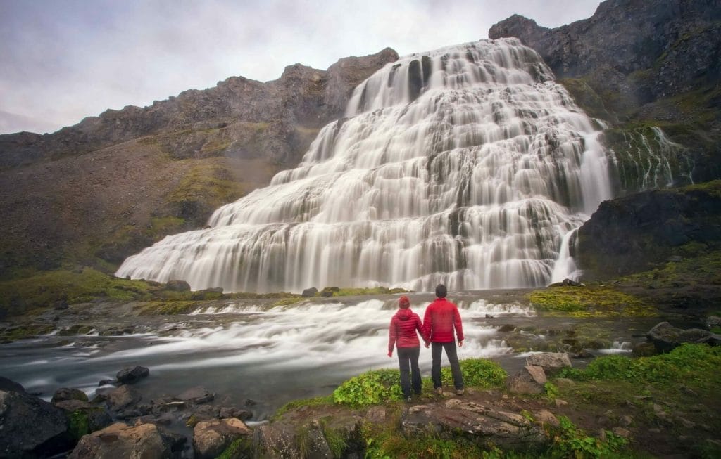 two people standing in front of Dynjandi waterfall in the Westfjords of Iceland