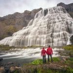 two people standing in front of Dynjandi waterfall in the Westfjords of Iceland