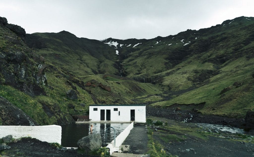 woman swimming in Seljavallalaug natural swimming pool in south Iceland