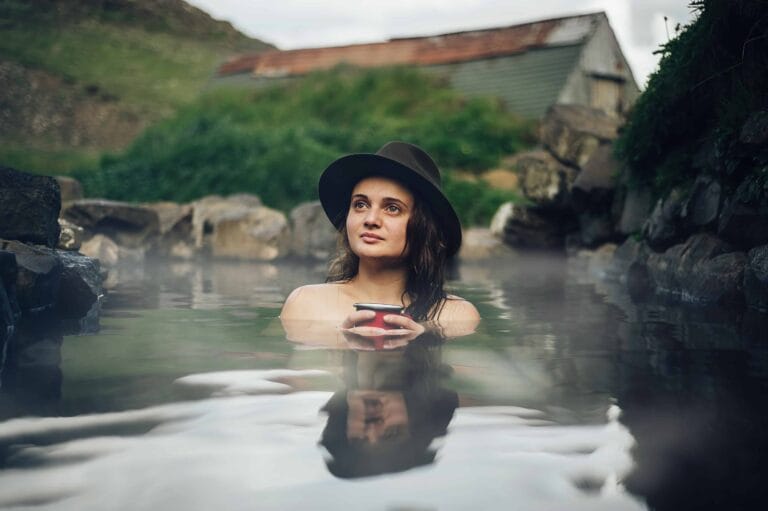 Iceland hot spring, woman sitting in Hrunalaug hot spring in the Golden Circle Iceland