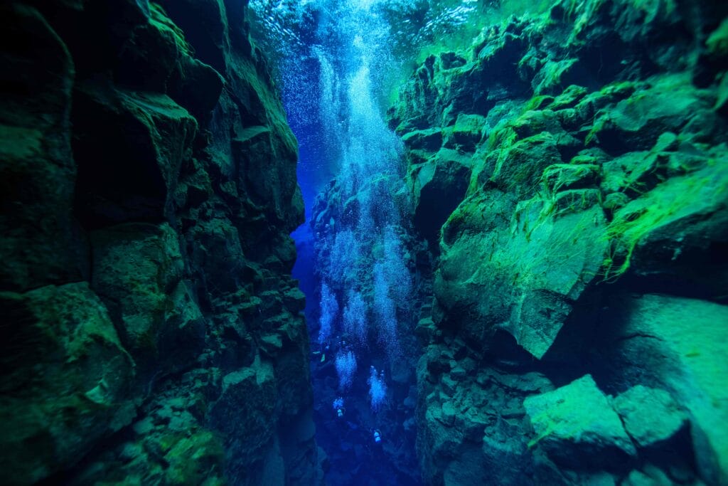 man diving in the clear water in Silfra in Thingvellir National Park in Iceland, man diving between the continents of Europe and North America