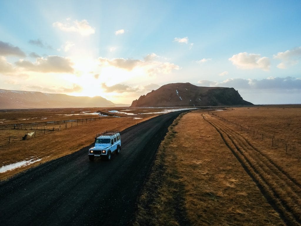 white jeep driving in a sunset in Iceland