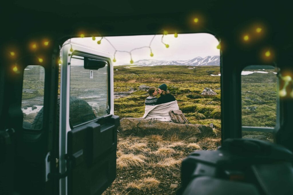 Two people in Icelandic wool sweater checking a map in a camper van in Iceland