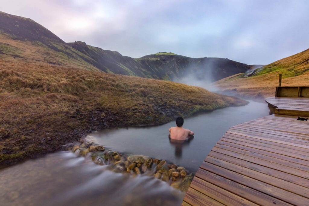 Iceland Hot Springs, hot springs in Iceland, man sitting in Reykjadalur hot spring on the Reykjadalur hot spring and hike