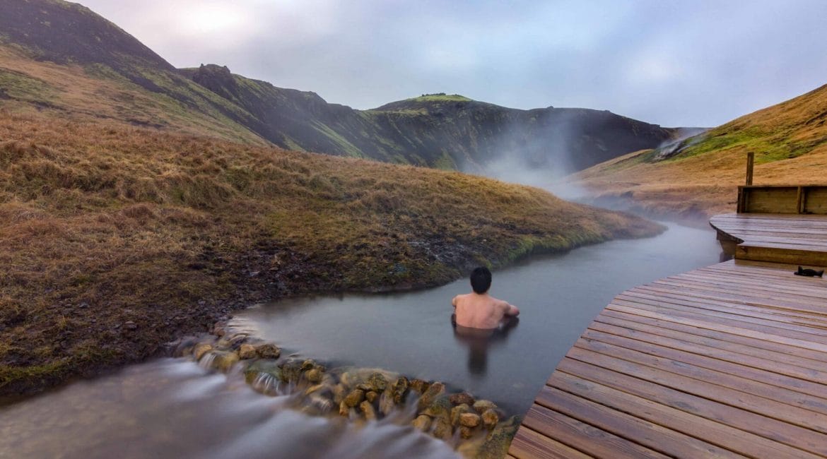 man sitting in Reykjadalur hot spring on the Reykjadalur hot spring and hike