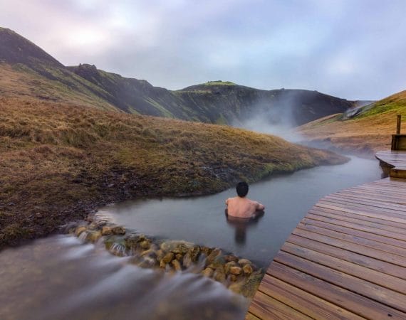 Iceland Hot Springs, hot springs in Iceland, man sitting in Reykjadalur hot spring on the Reykjadalur hot spring and hike
