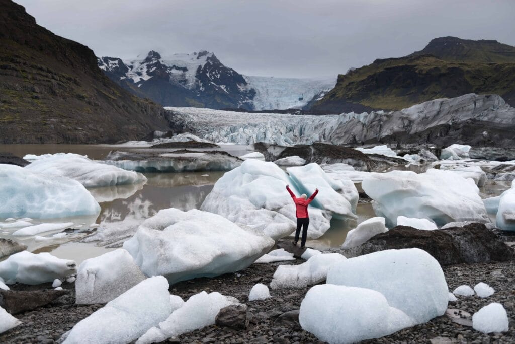 woman in pink coat next to Svínafellsjokull glacier in south Iceland