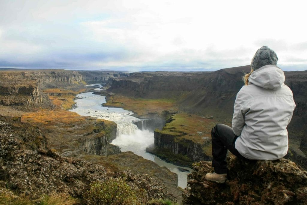 woman sitting at the viewpoint at Hafragilsfoss waterfall in the diamond circle in north Iceland