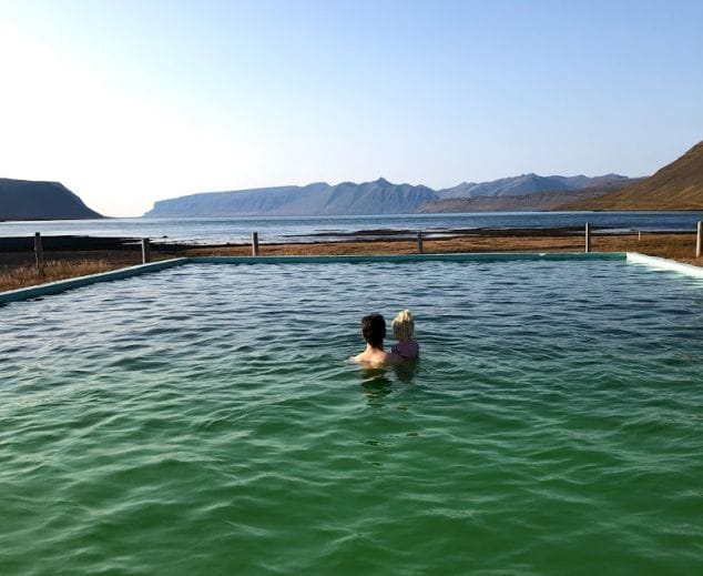 father and daughter looking at the amazing views from Reykjafjarðarlaug swimming pool in the westfjords of Iceland