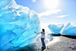 girl standing in front of an ice berg at the Diamond beach in South Iceland