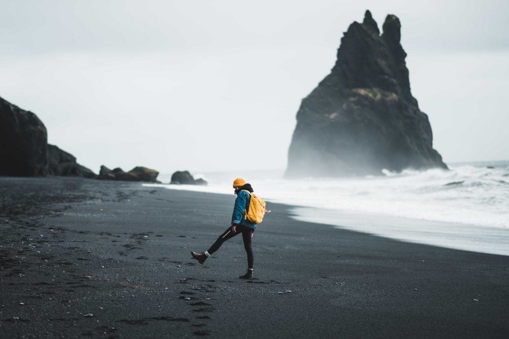 man with a Daypack in Iceland at Reynisfjara black sand beach