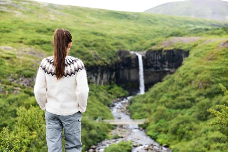 Woman Standing in an Icelandic wool sweater in front of Svartifoss Waterfall in Skaftafell National Park - Iceland Tours Booking
