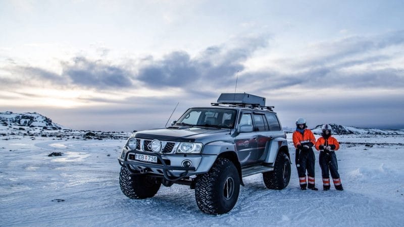man standing next to a large jeep on Eyjafjallajokull glacier and volcano