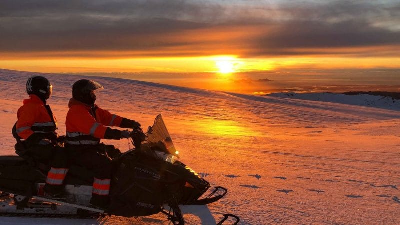 Iceland Snowmobile Tour, Snowmobile Iceland, Snowmobiling in Iceland, two people watching the sunset on Eyjafjallajokull glacier and volcano snowmobile tour