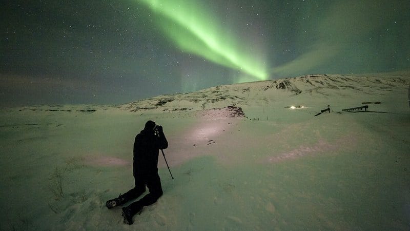 man taking a photo of the Northern lights in Iceland