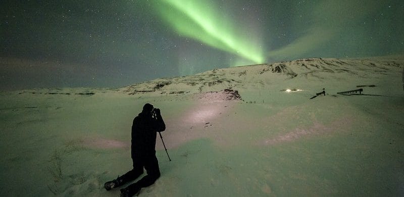 man taking a photo of the Northern lights in Iceland