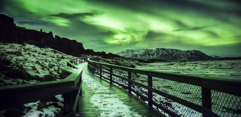 Northern Lights Above Þingvellir National Park: A dramatic scene of the Northern Lights shining over Þingvellir National Park in Iceland. The aurora's vibrant colors illuminate the unique geological formations and vast landscape below.