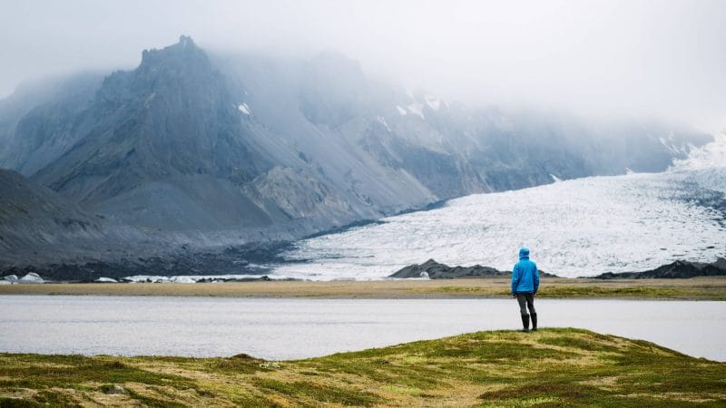 man standing in front of Breiðárlón glacier lagoon and Vatnajokull glacier in south Iceland