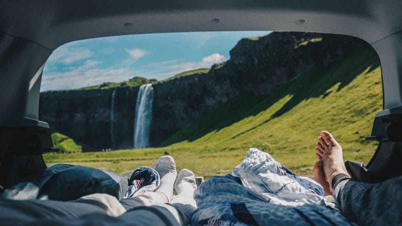 relaxing in the back of a camper van in front of Seljalandsfoss waterfall in South Iceland