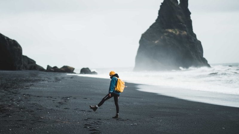 man with a Daypack in Iceland at Reynisfjara black sand beach