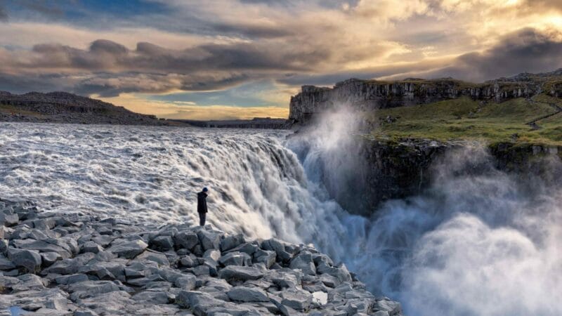 man standing in front of Dettifoss the most powerful waterfall in Europe