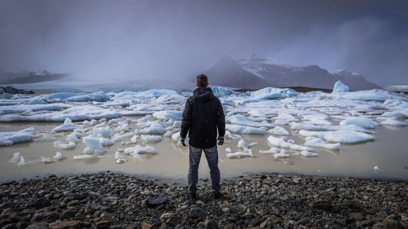 Man Standing in Front of Fjallsárlón Glacier Lagoon - South Iceland Tours