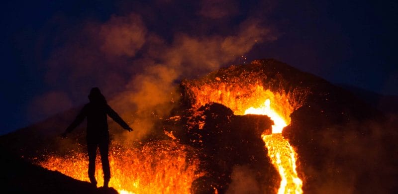 active volcano tour, man standing in front of Geldingadalur erupting volcano in Iceland