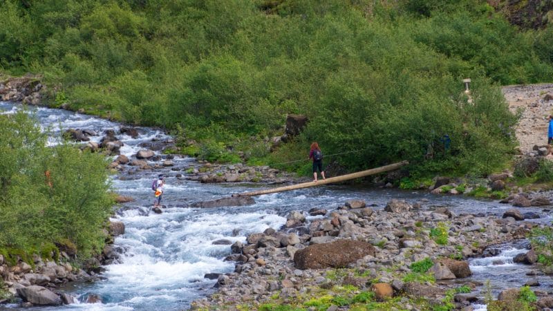 walking over a wooden bridge over a river on the way to Glymur waterfall in west Iceland