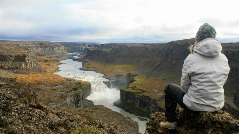 woman sitting at the viewpoint at Hafragilsfoss waterfall in the diamond circle in north Iceland
