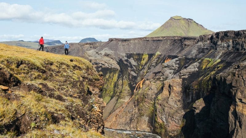 two man standing on top of a canyon watching the views