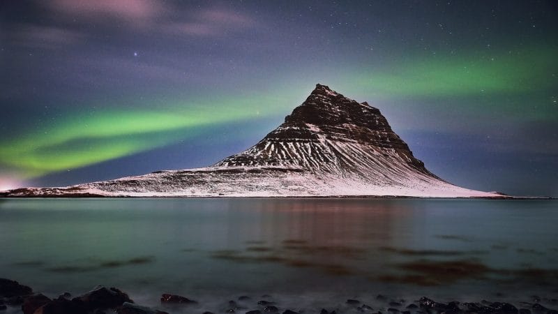 northern lights aurora borealis dancing over Kirkjufell mountain and Kirkjufellsfoss waterfall in Snæfellsnes Peninsula