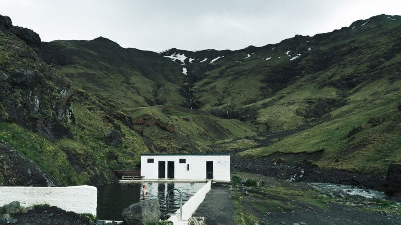 woman swimming in Seljavallalaug natural swimming pool in south Iceland