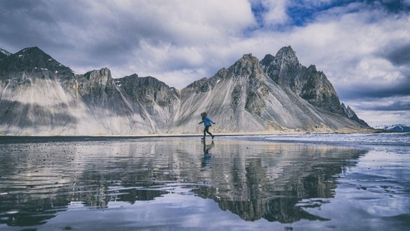 woman walking on the mirror beach at Vestrahorn and Stokksnes in south east Iceland
