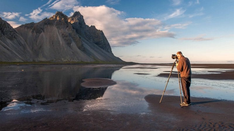 Man photographing Vestrahorn mountain from Stokksnes black sand beach in south east Iceland