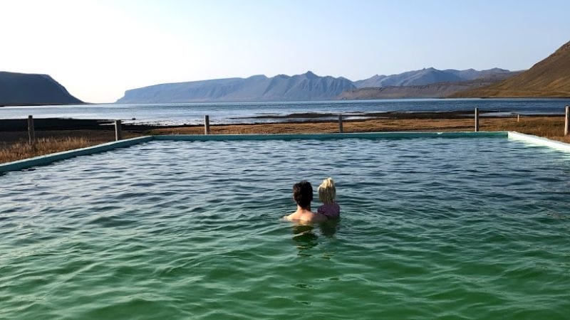father and daughter looking at the amazing views from Reykjafjarðarlaug swimming pool in the westfjords of Iceland