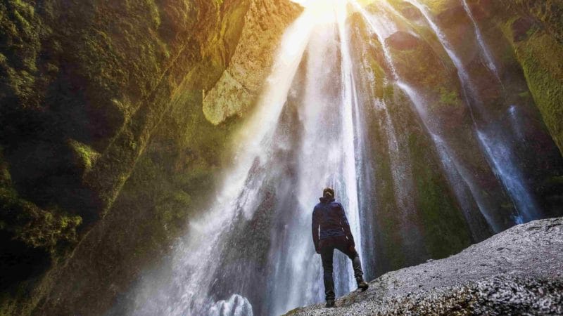 woman standing inside the canyon watching Gljufrabui waterfall in south Iceland