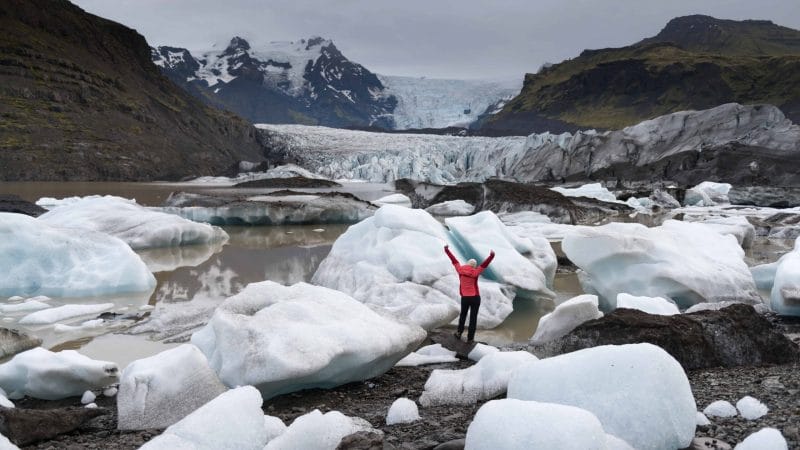 woman in pink coat next to Svínafellsjokull glacier in south Iceland