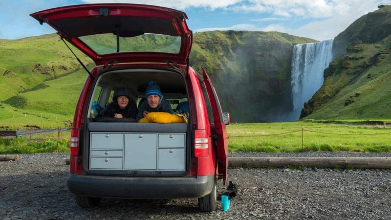 two people in a camper van next to Skógafoss in south Iceland