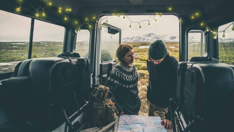 Two people in Icelandic wool sweater checking a map in a camper van in Iceland