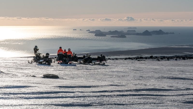 people on Eyjafjallajokull snowmbobile tour with views over Vestmannaeyjar islands in south Iceland