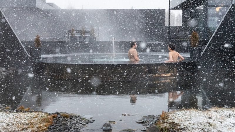 snow falling on two people at Krauma geothermal baths and spa in west Iceland during winter