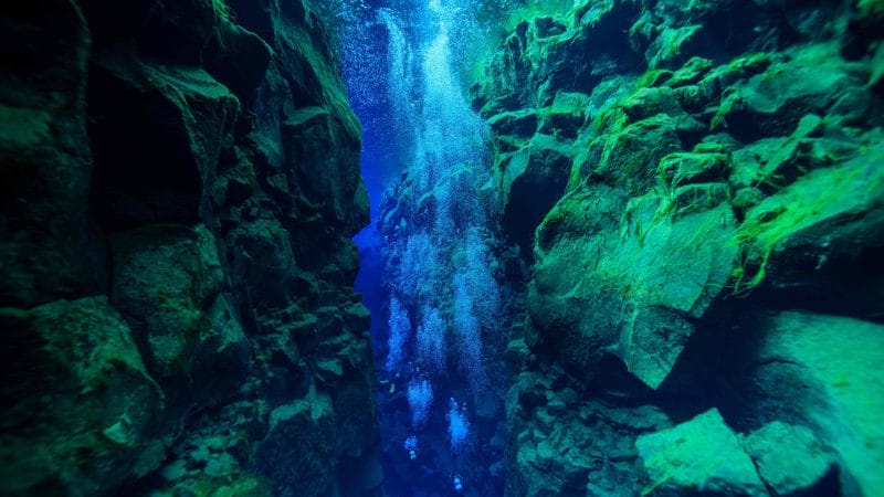 man diving in the clear water in Silfra in Thingvellir National Park in Iceland, man diving between the continents of Europe and North America